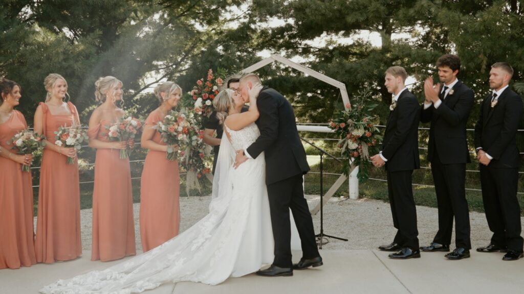 Couple just married on their wedding day you may now kiss the bride and they kiss.  Filmed in a relaxed, cinematic wedding video style.